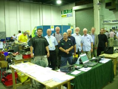 Photograph of the FISTS stand at Donnington in 2007 including Mark M0BLT, Rob M0BPT, Roy G4PRL, John M0CDL, Peter M5ABN, Bob G6GUN, Derek M0DRK and two unknown people.